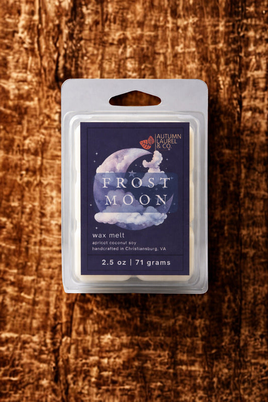 Frost Moon 2.5 oz wax melt clamshell by Autumn Laurel displayed on dark amber-toned wood with moody Appalachian-inspired styling.