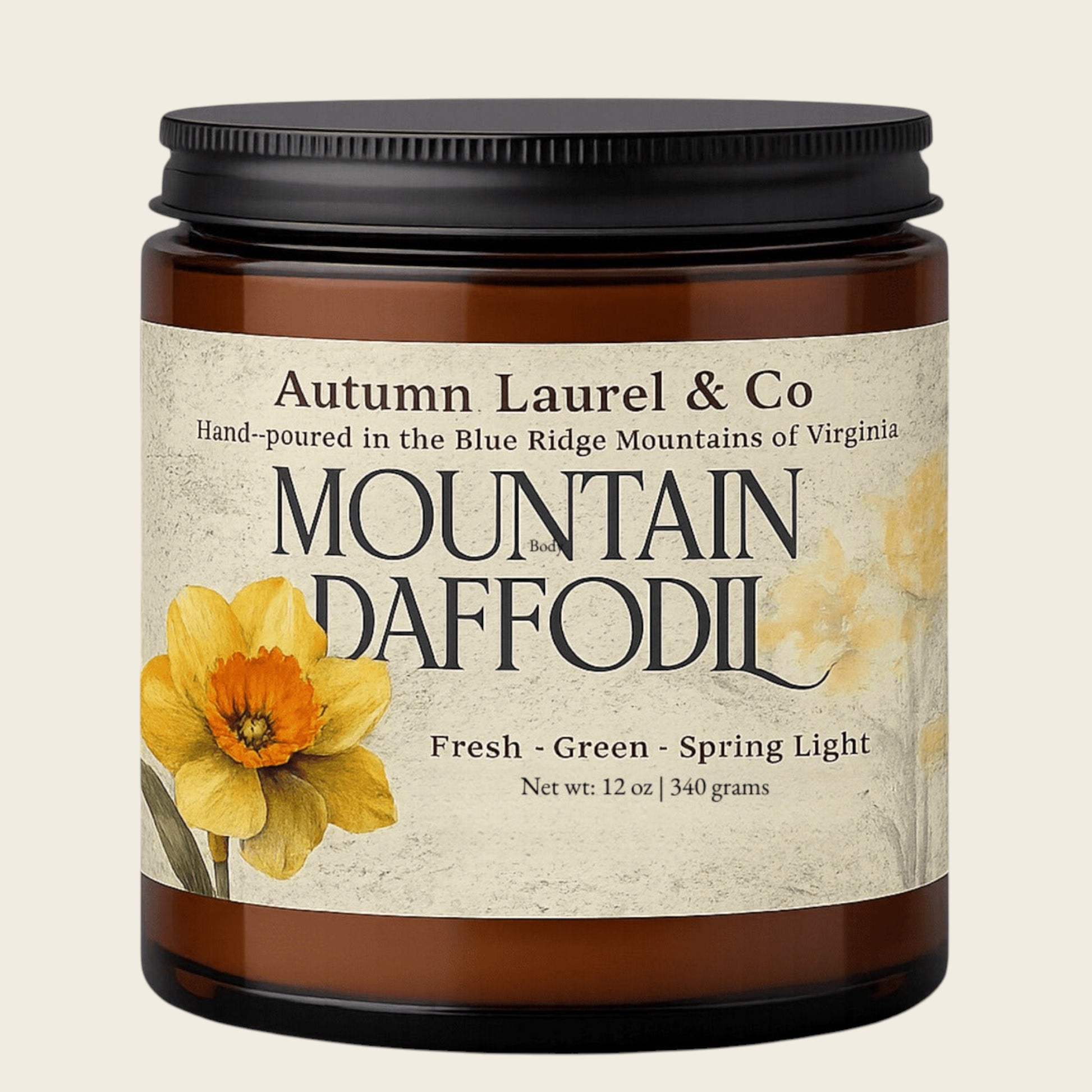 An amber glass jar candle with a black lid and a cream-colored label featuring yellow daffodil flowers and the text 'Autumn Laurel & Co' and 'Mountain Daffodil'.