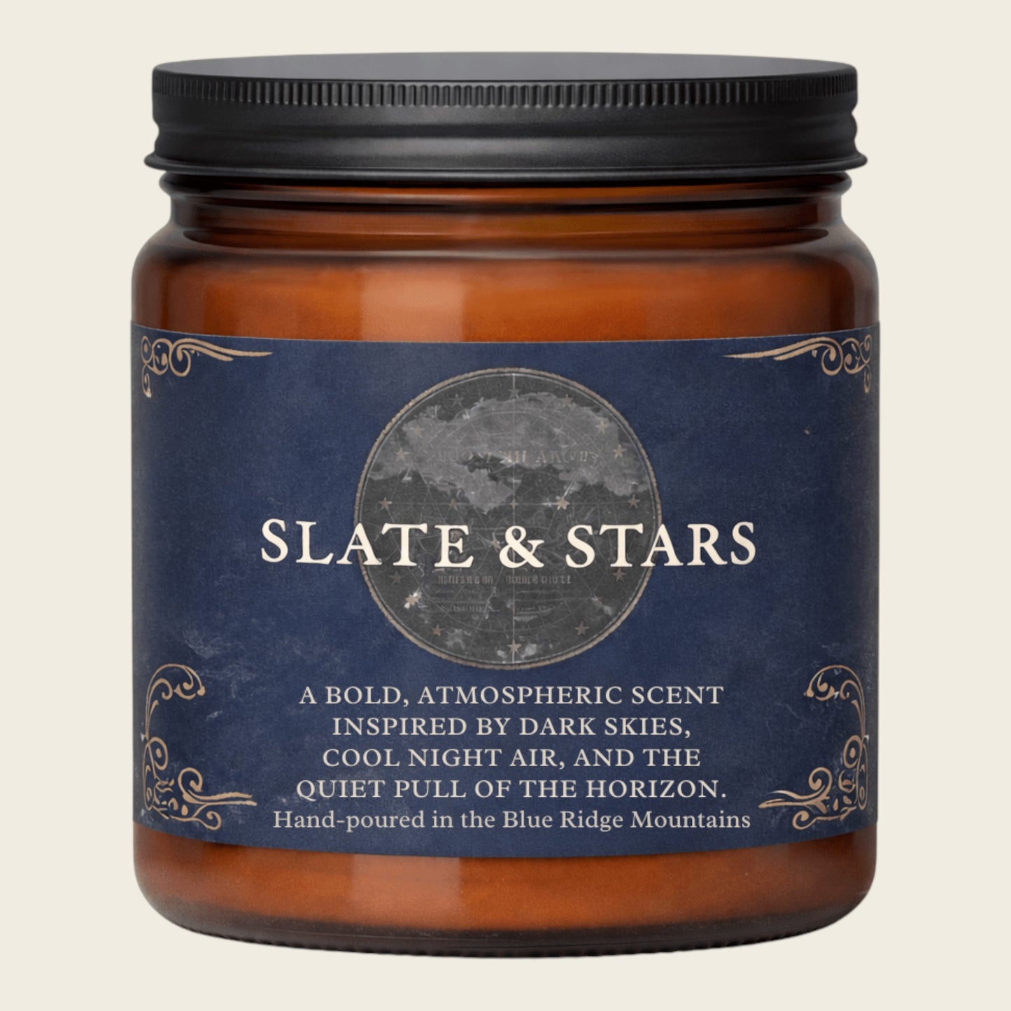 An amber glass jar candle with a black screw-on lid and a dark blue label reading 'SLATE & STARS' with scent and hand-poured location text, shown on a light beige background.