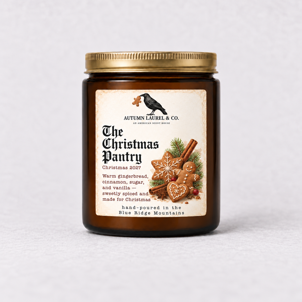 The Christmas Pantry amber candle with gold lid and raven carrying a gingerbread cookie